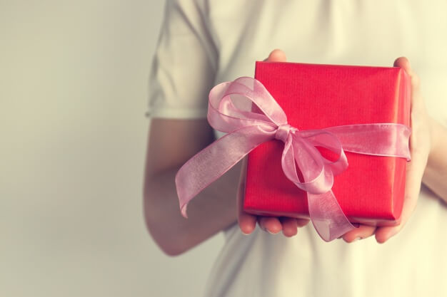 woman in white t-shirt holding red gift with pink ribbon