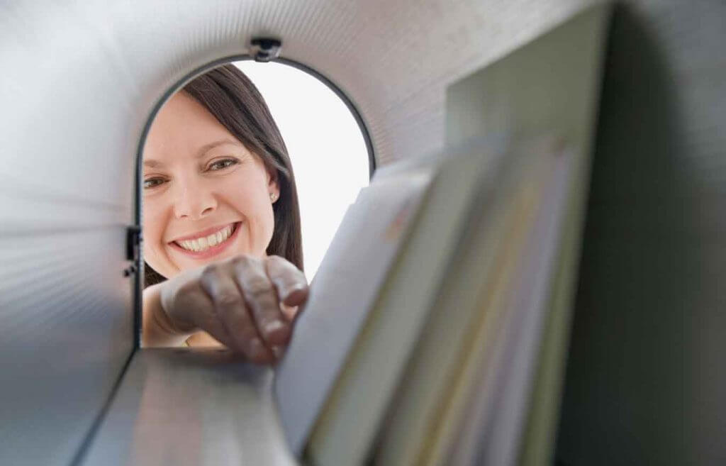 Smiling woman removing mail from mailbox