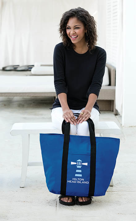 Young woman smiling and holding blue branded tote bag