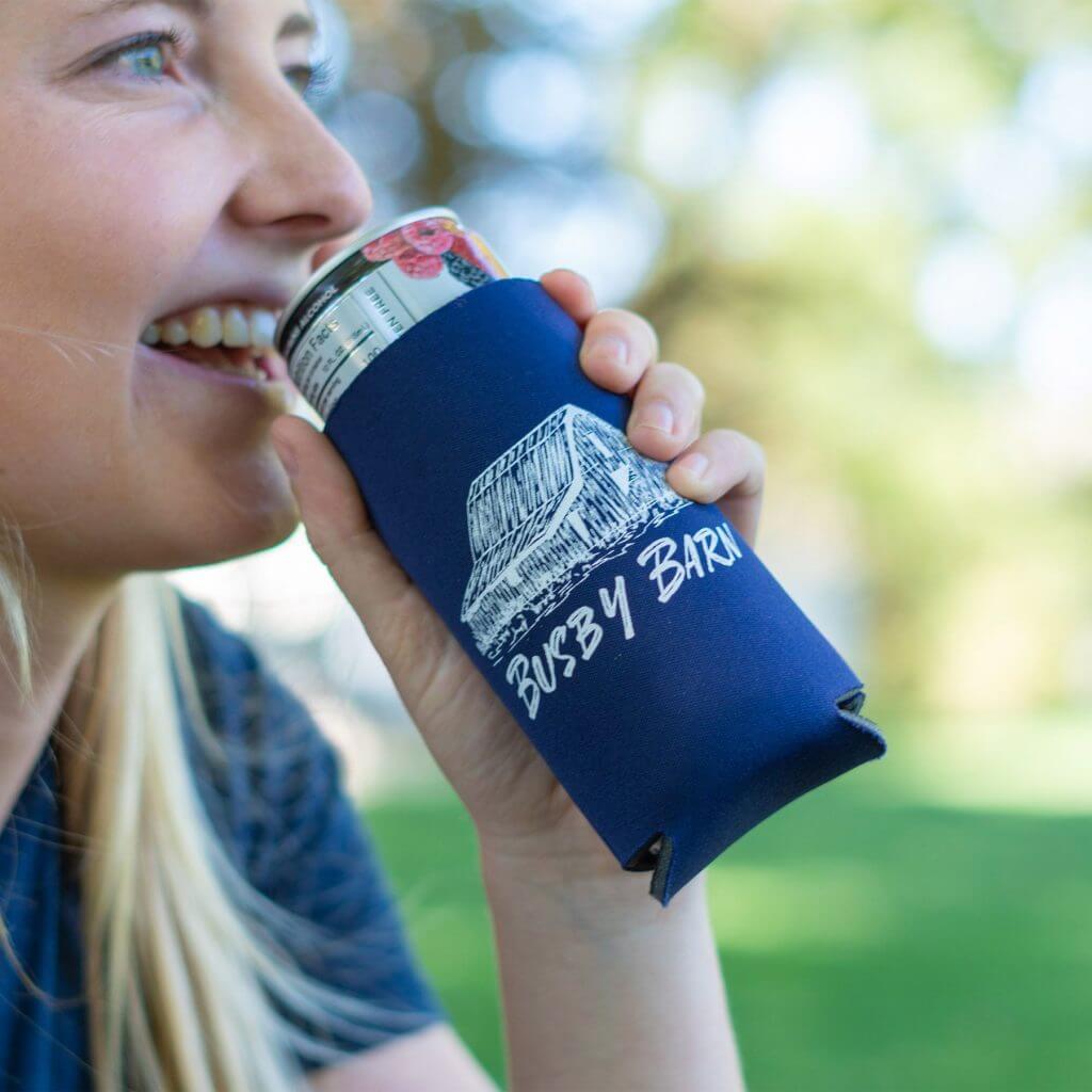 Young woman drinking from can with blue branded koozie