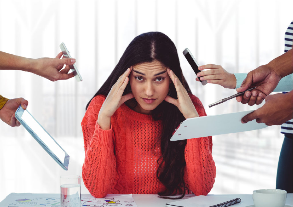 Stressed woman at desk surrounded by distractions